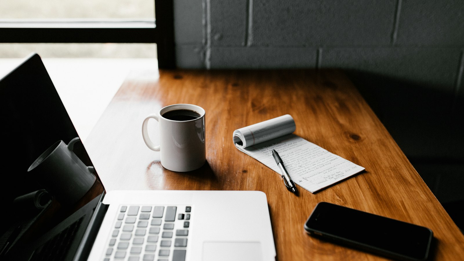 A laptop, coffee and notes on a wooden table