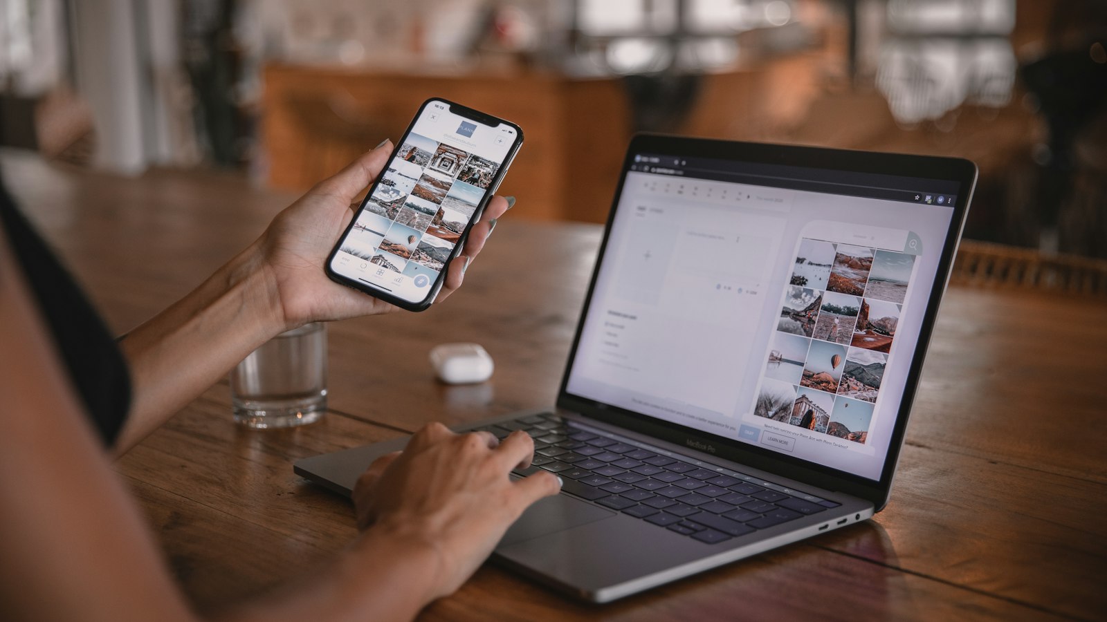 Someone using a phone and a laptop at a cafe table