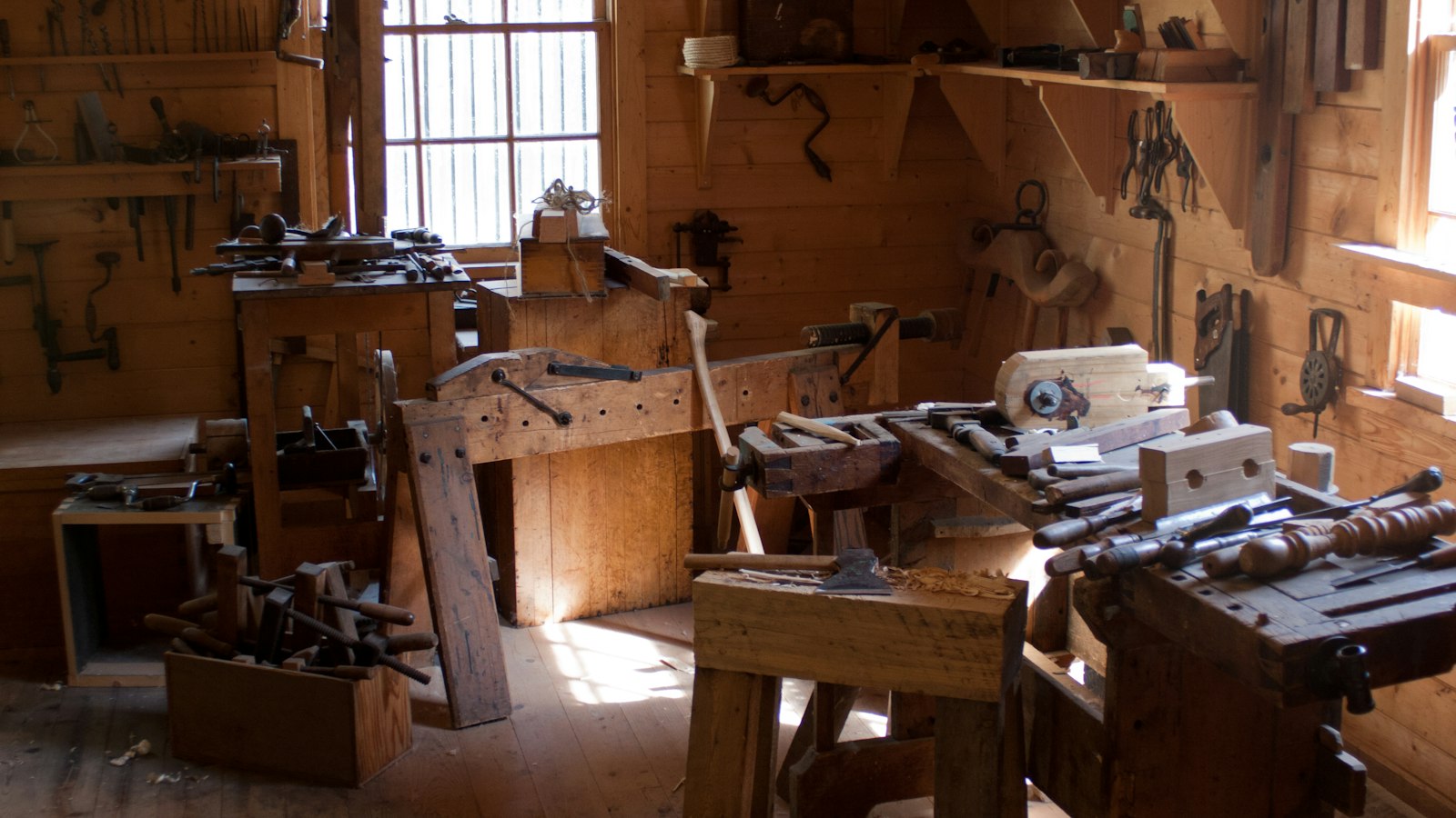 A carpentry workshop with tools and workbenches in warm light
