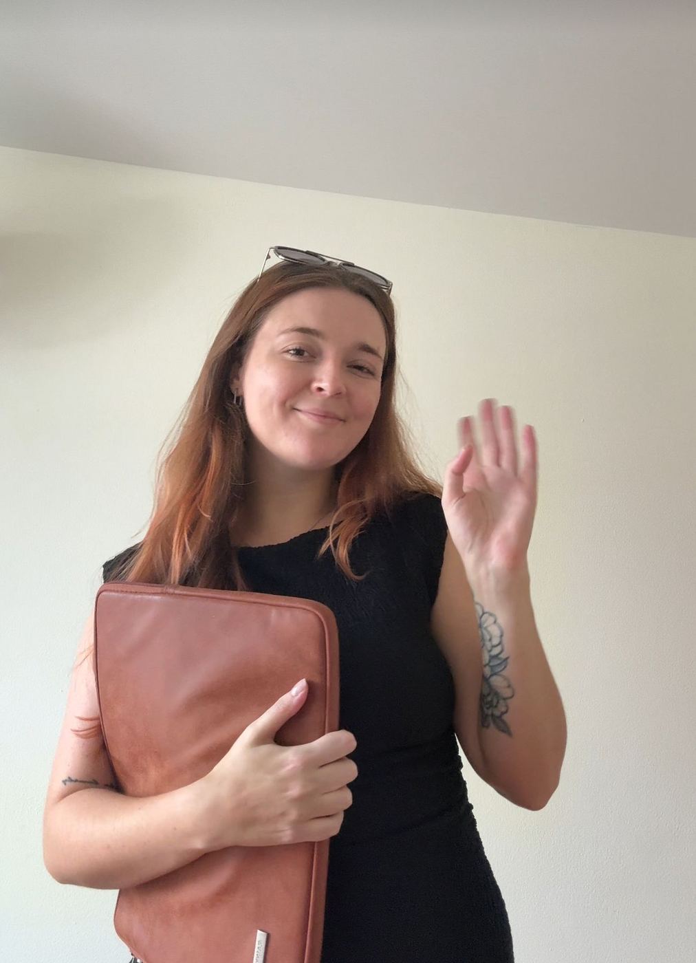 Indi waving hello, laptop bag in hand