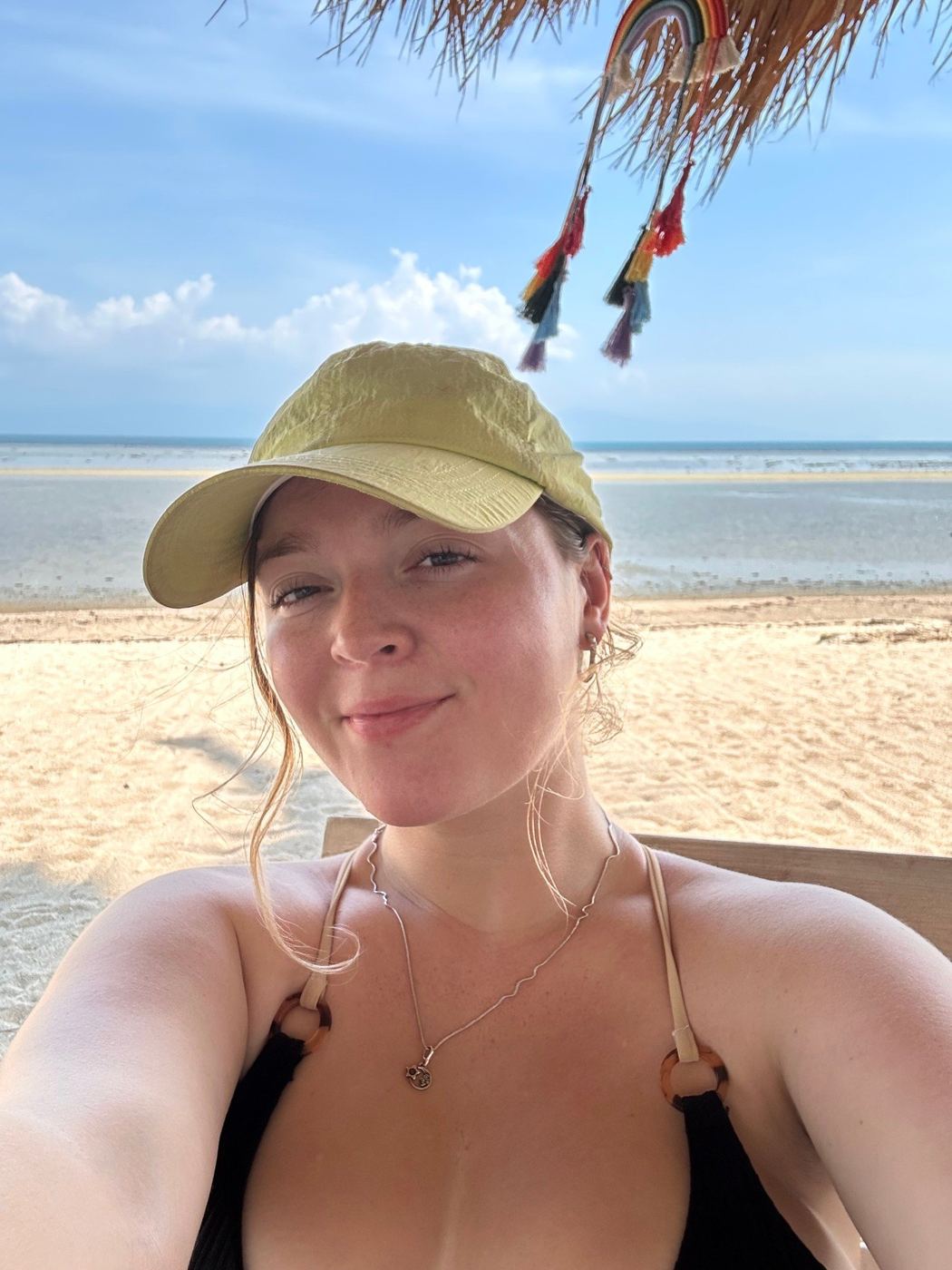 Beach selfie under a thatched umbrella, sea behind
