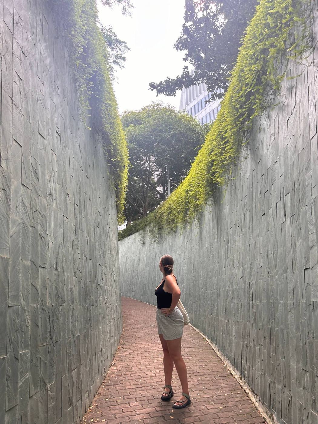 Indi smiling in front of a wall of green plants